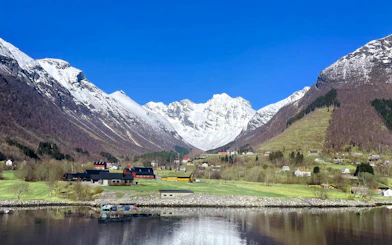 Hjørundfjord landscape with snow-capped mountains and village, Norway.