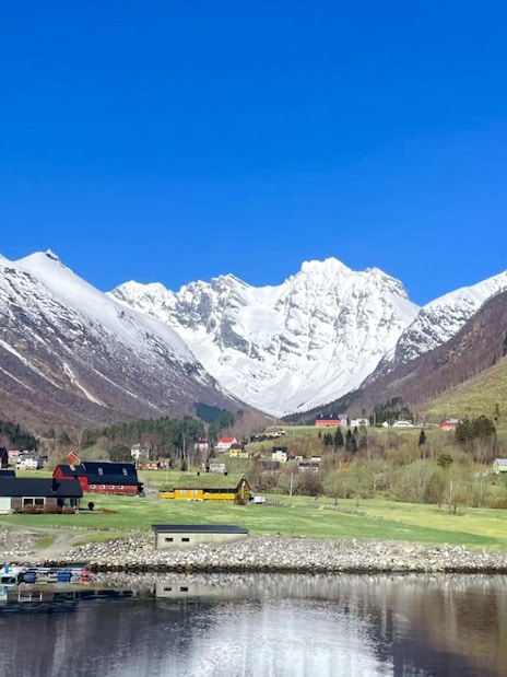 Hjørundfjord landscape with snow-capped mountains and village, Norway.