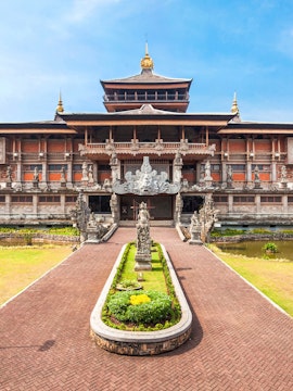 Taman Mini Indonesia traditional building with ornate statues and garden path.