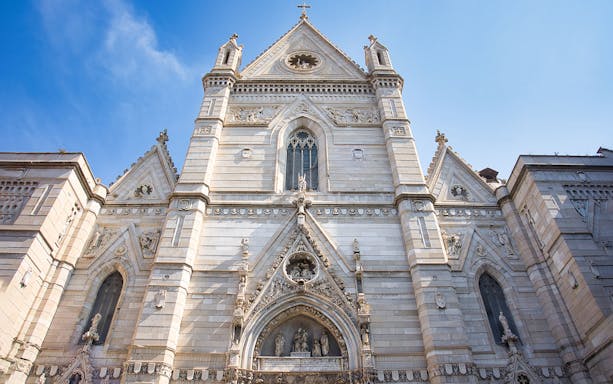 Naples Cathedral facade with intricate Gothic architecture under a clear blue sky.