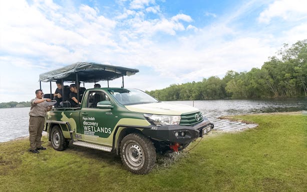 Safari vehicle at Paya Indah Discovery Wetlands, Gamuda Cove, near a lake with tourists.