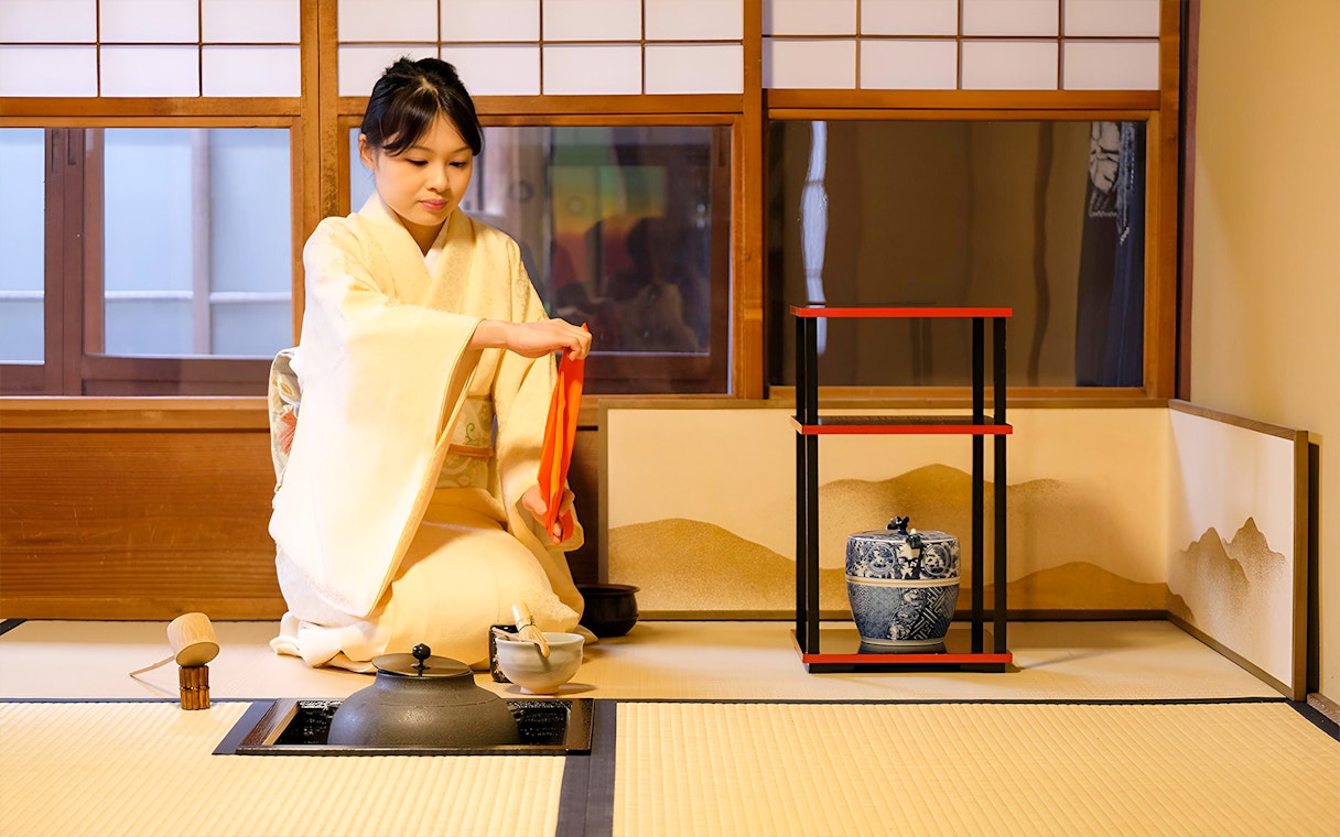 Tea ceremony in Kyoto with woman in kimono preparing tea.
