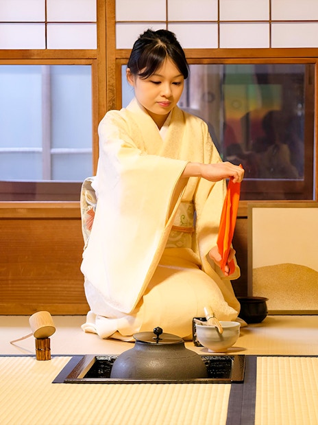 Tea ceremony in Kyoto with woman in kimono preparing tea.