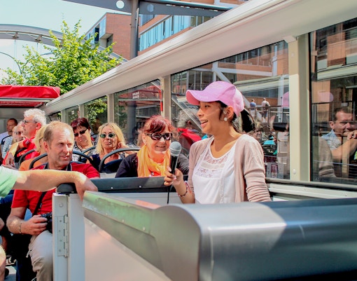 Tour guide speaking to passengers on a city bus tour.