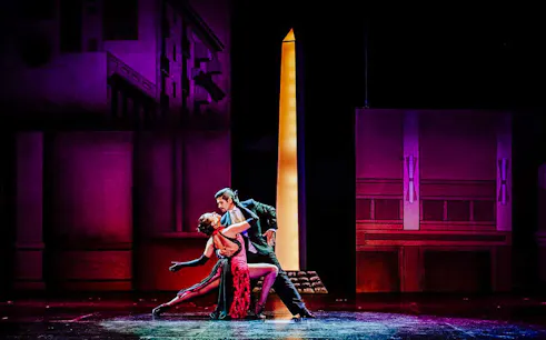 Dancers performing at Tango Porteño Show in front of a lit backdrop.