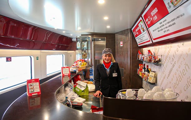 Train cafe with staff member and snacks, Italy train pass experience.