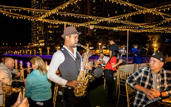 Saxophonist performing on a Dubai Marina sunset cruise with buffet dinner.