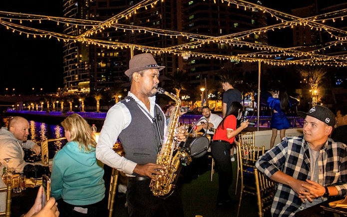 Saxophonist performing on a Dubai Marina sunset cruise with buffet dinner.