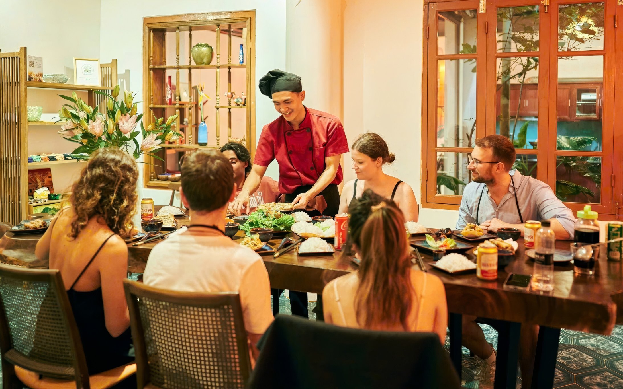 Chef teaching a group at a traditional Vietnamese cooking class in a cozy dining room.