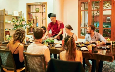 Chef teaching a group at a traditional Vietnamese cooking class in a cozy dining room.