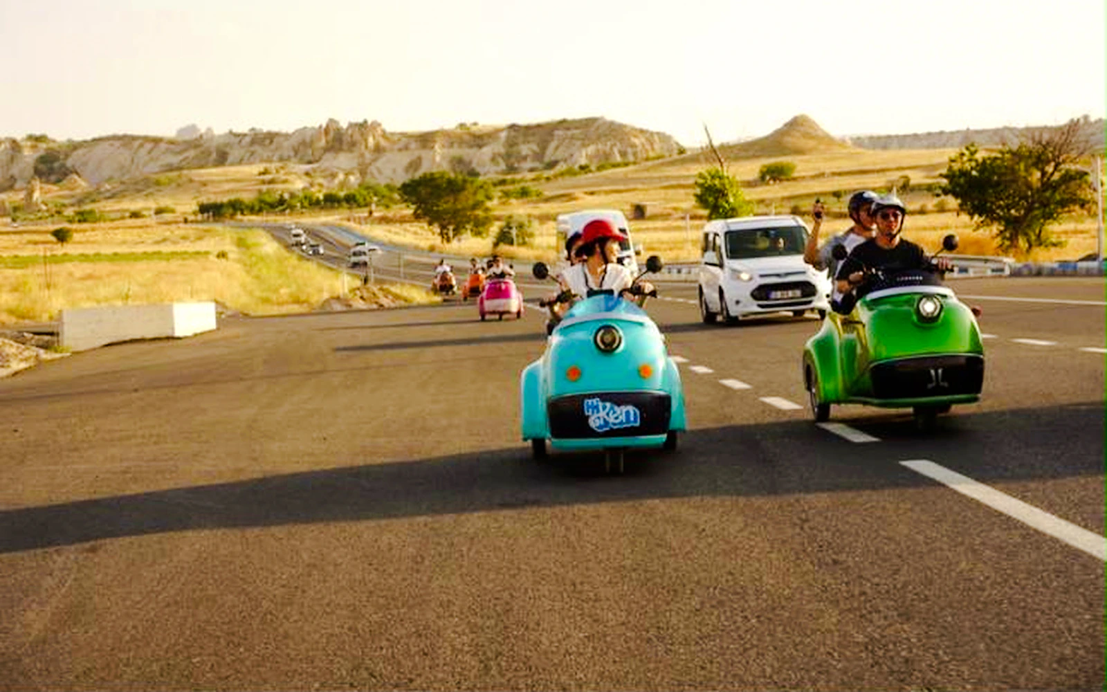 Vintage electric carts on a road in Love Valley, Cappadocia, with scenic rock formations.