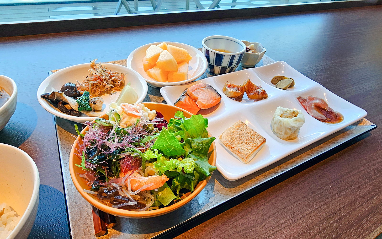 Assorted dishes at Lavabeach Restaurant Tenerife, featuring fresh salad, salmon, and fruit.