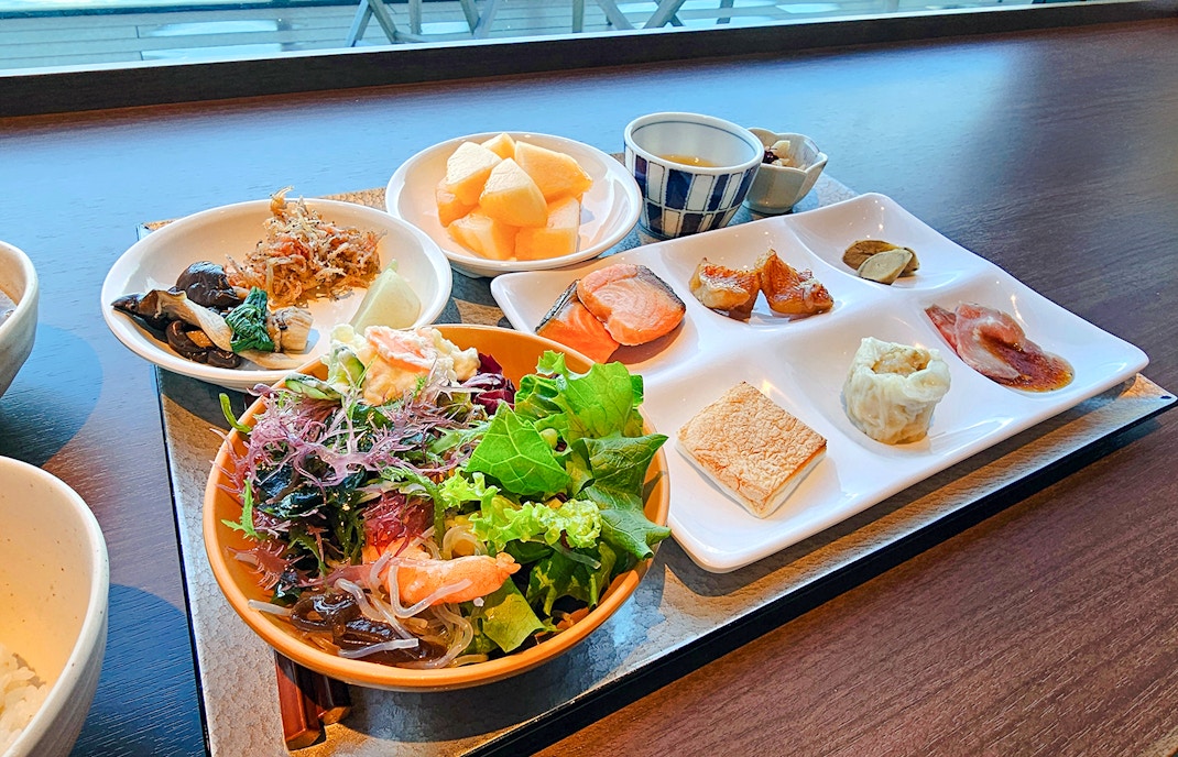 Assorted dishes at Lavabeach Restaurant Tenerife, featuring fresh salad, salmon, and fruit.