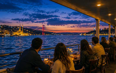 People dining on a yacht with a view of the Bosphorus Bridge at sunset, Istanbul.
