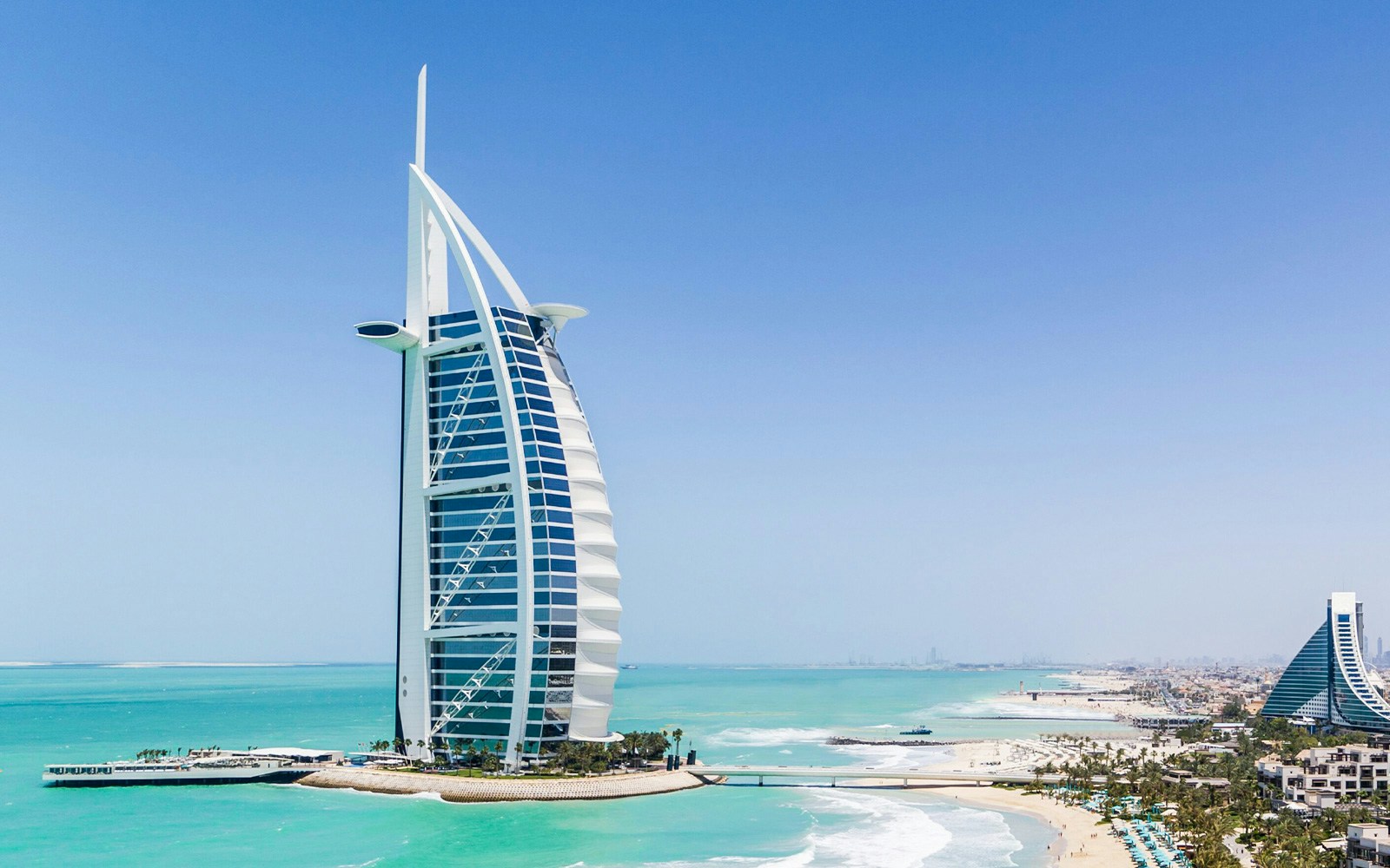 Burj Al Arab hotel on the coast of Dubai with turquoise sea and beach.