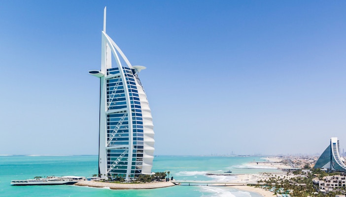 Burj Al Arab hotel on the coast of Dubai with turquoise sea and beach.