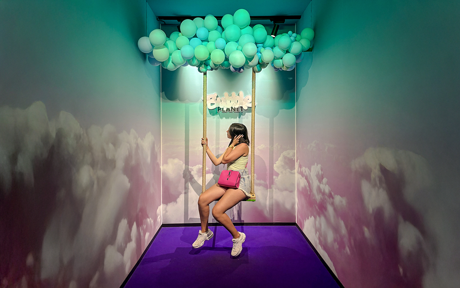 Guest on swing under balloon ceiling at Bubble Planet Berlin.