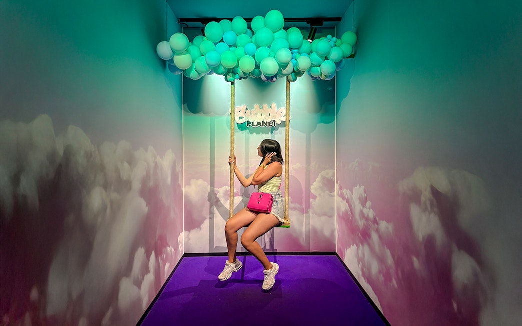 Guest on swing under balloon ceiling at Bubble Planet Berlin.