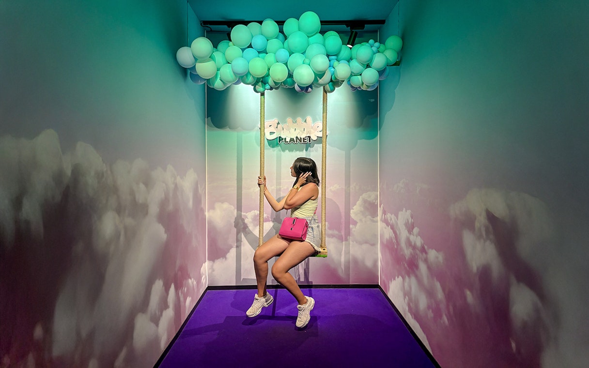 Guest on swing under balloon ceiling at Bubble Planet Berlin.