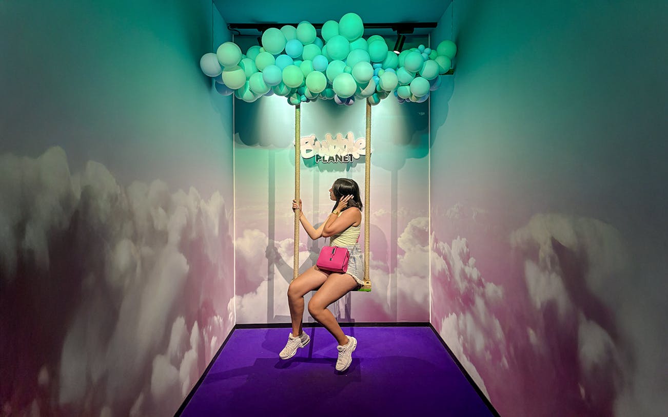 Guest on swing under balloon ceiling at Bubble Planet Berlin.