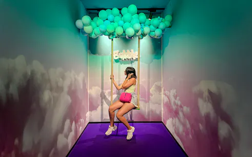 Guest on swing under balloon ceiling at Bubble Planet Berlin.