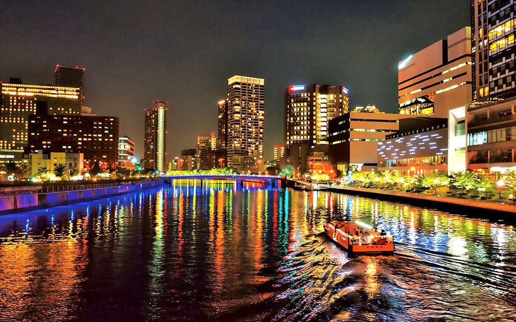 Nakanoshima River Cruise on Dojima River at night, Osaka, Japan, with city lights reflecting on water.