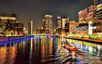 Nakanoshima River Cruise on Dojima River at night, Osaka, Japan, with city lights reflecting on water.