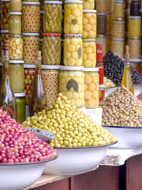 Jars and bowls of olives at a market stall during a Marrakech night walking tour.