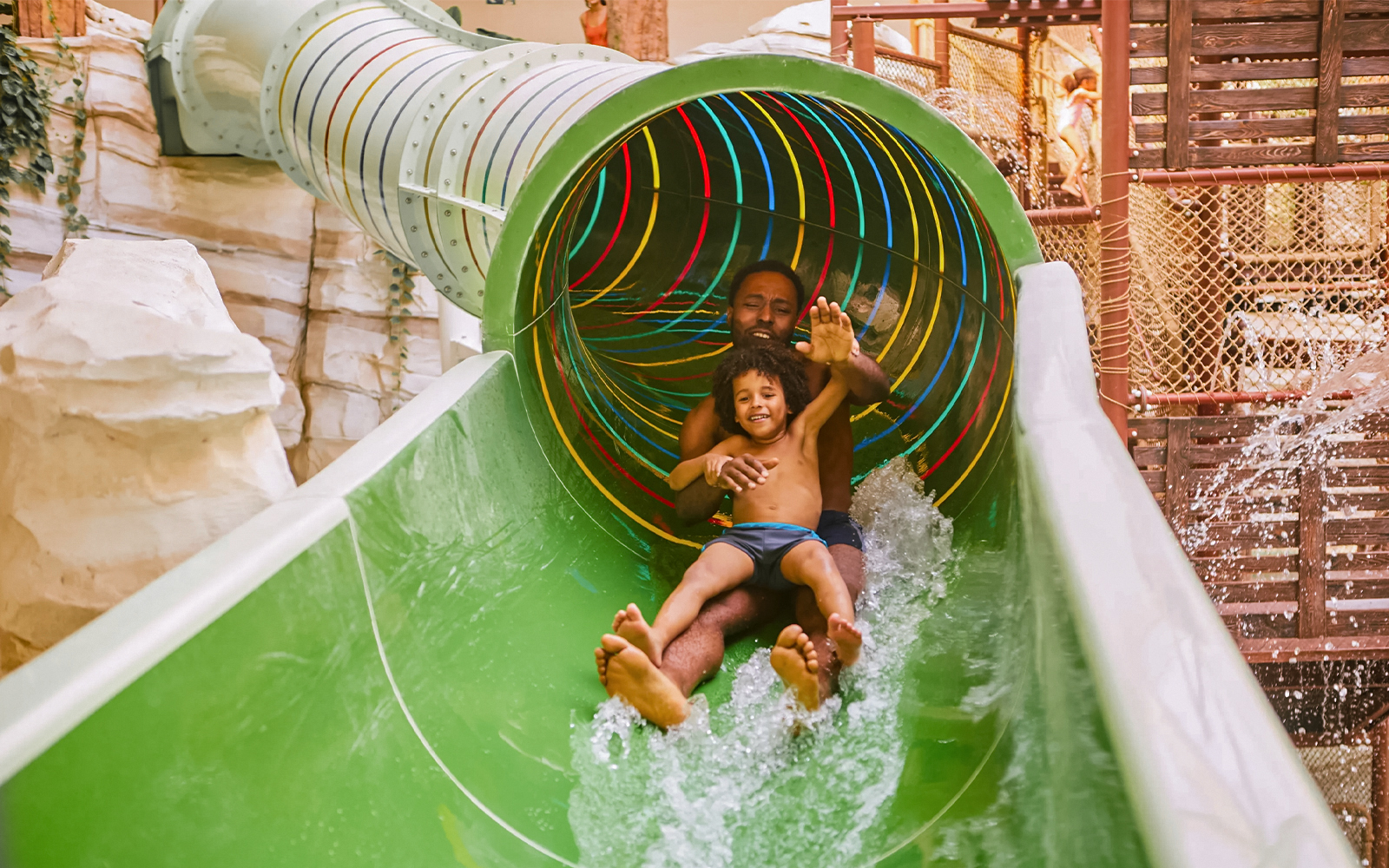 Father and child sliding down a colorful water slide at Bellewaerde Aquapark, Ypres.