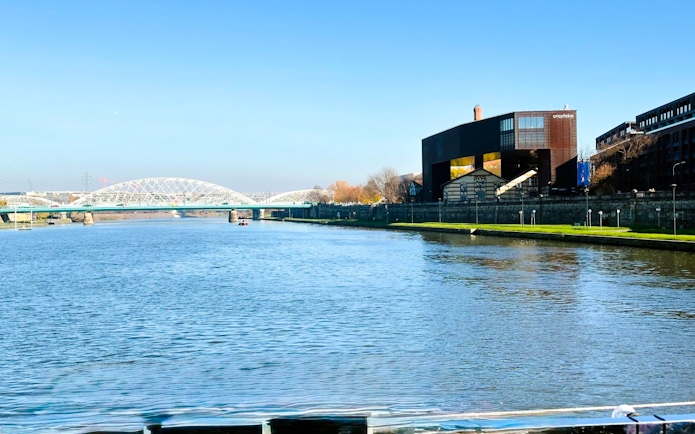 Vistula River in Kraków with Cricoteka and bridge during river cruise.