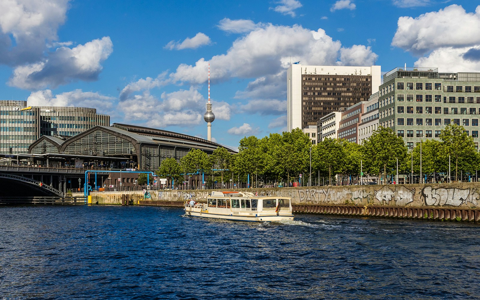 Boat cruising on the Spree River with Berlin's TV Tower and cityscape in the background.