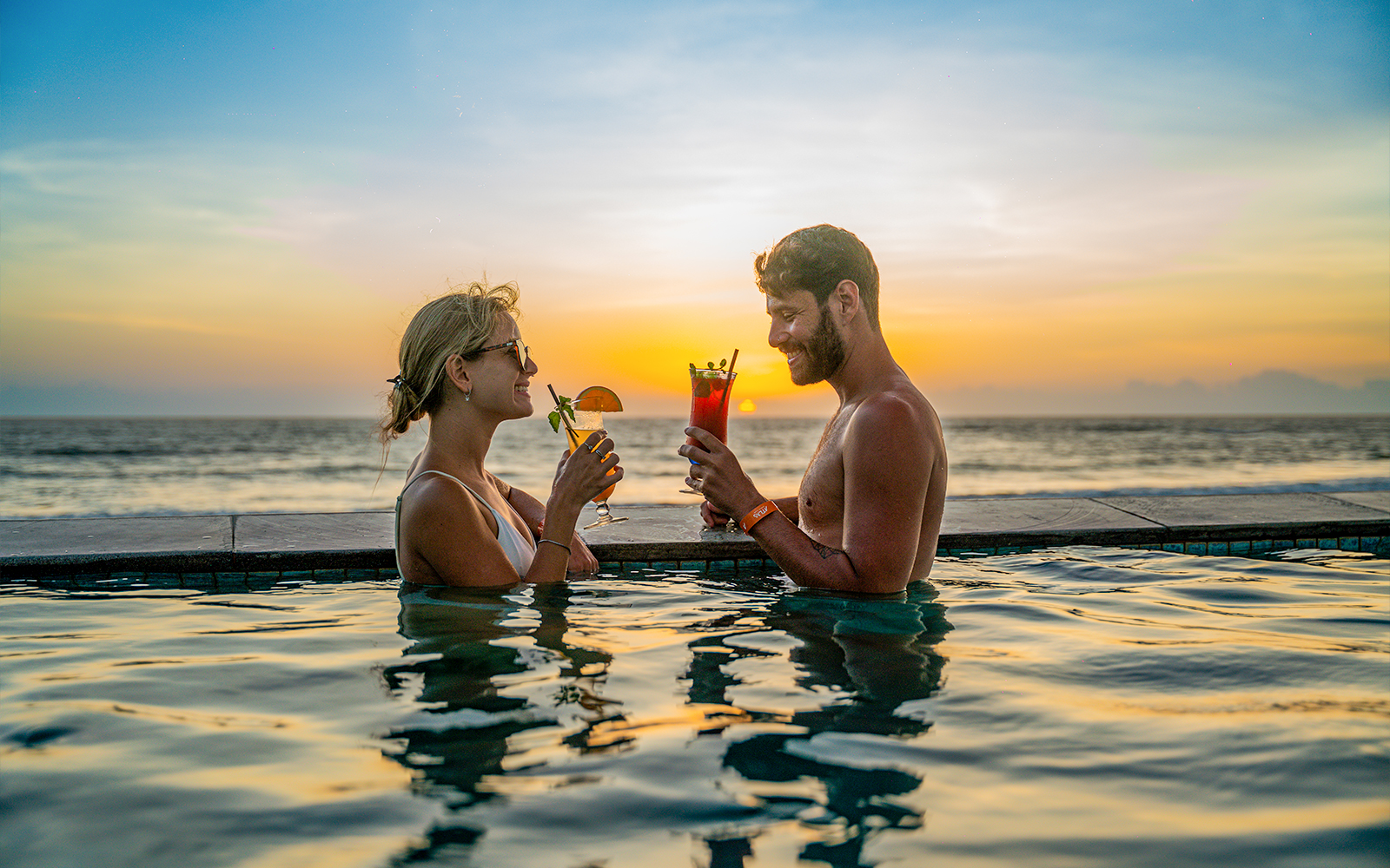 Couple enjoying drinks in a pool at sunset, Atlas Beach Club.