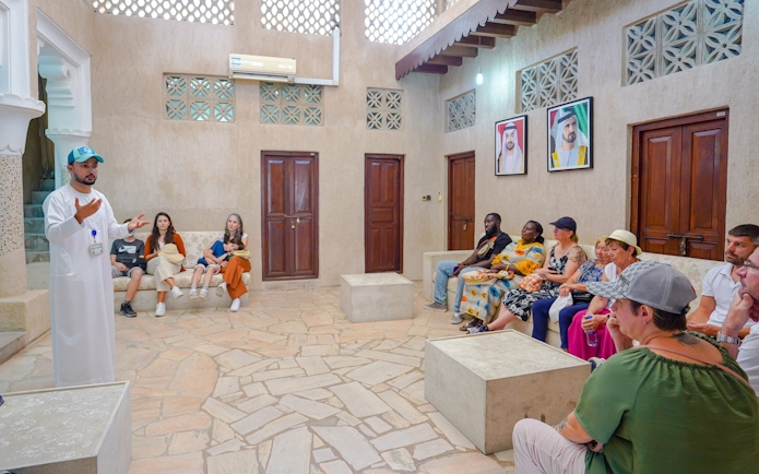 Guide engaging with tourists in a traditional room, Dubai.