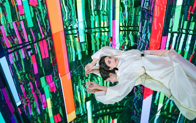 Woman in white dress at Tides zone, AYA Universe, Dubai, with colorful reflections.