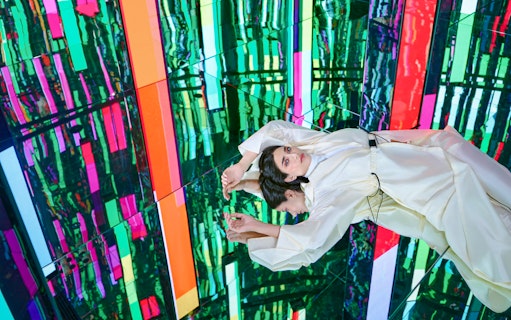 Woman in white dress at Tides zone, AYA Universe, Dubai, with colorful reflections.