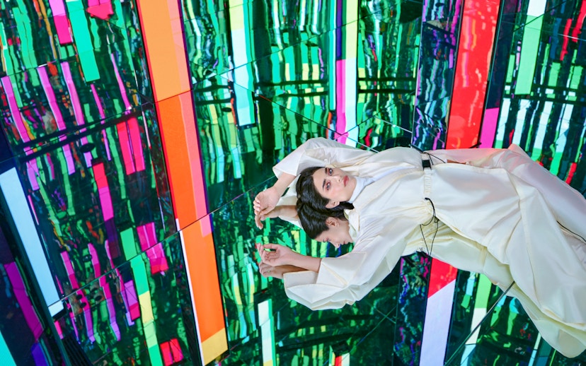 Woman in white dress at Tides zone, AYA Universe, Dubai, with colorful reflections.