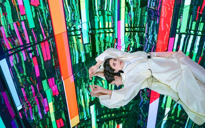 Woman in white dress at Tides zone, AYA Universe, Dubai, with colorful reflections.