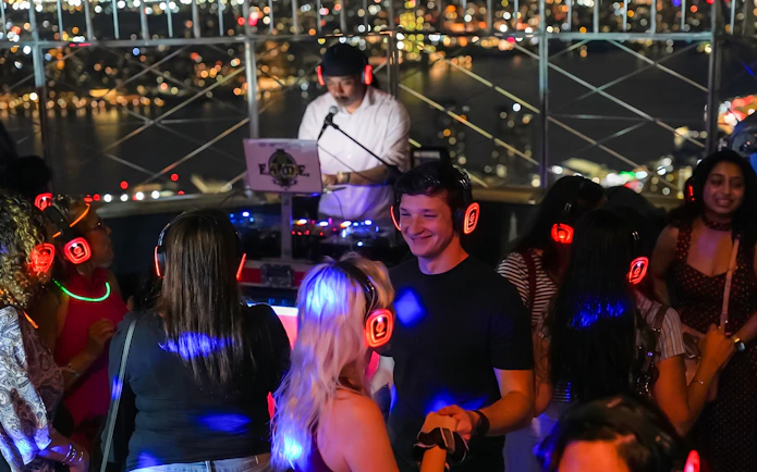 People enjoying a silent disco with headphones at the Empire State Building Observation Deck.