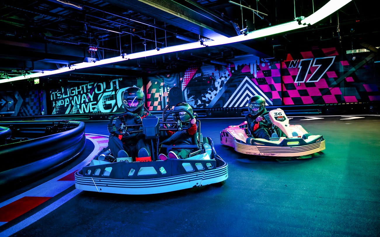 Guests racing go-karts indoors during F1 London Mixed session.