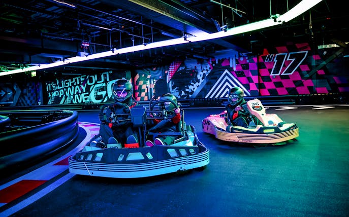 Guests racing go-karts indoors during F1 London Mixed session.