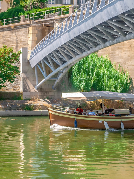 Tourists on a Douro Valley cruise boat passing under a bridge.