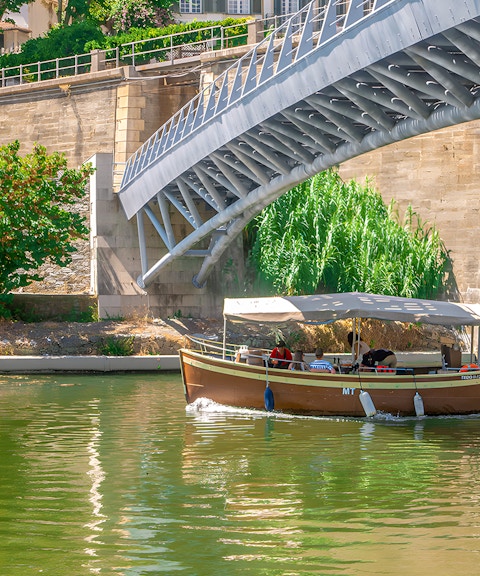 Tourists on a Douro Valley cruise boat passing under a bridge.