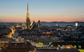 Vienna skyline at sunset featuring St. Stephen's Cathedral spire, part of a self-guided city exploration game.