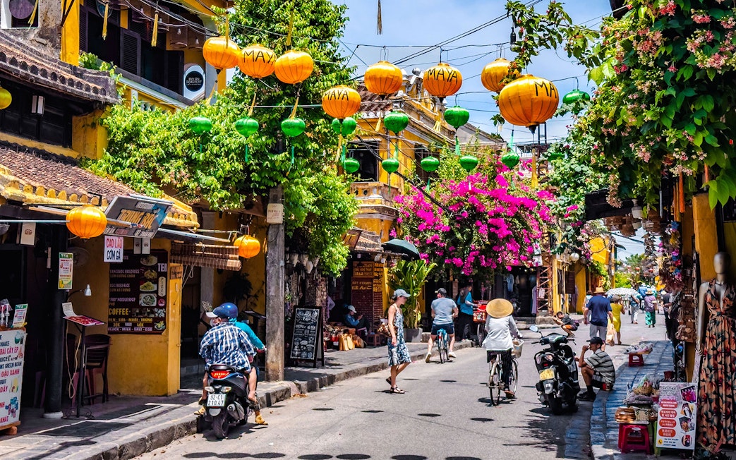 Street view in Hoi An ancient town, Vietnam, with colorful lanterns and vibrant flowers.