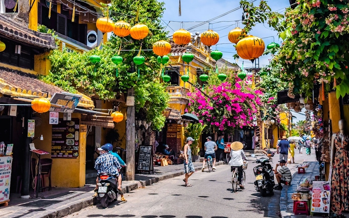 Street view in Hoi An ancient town, Vietnam, with colorful lanterns and vibrant flowers.