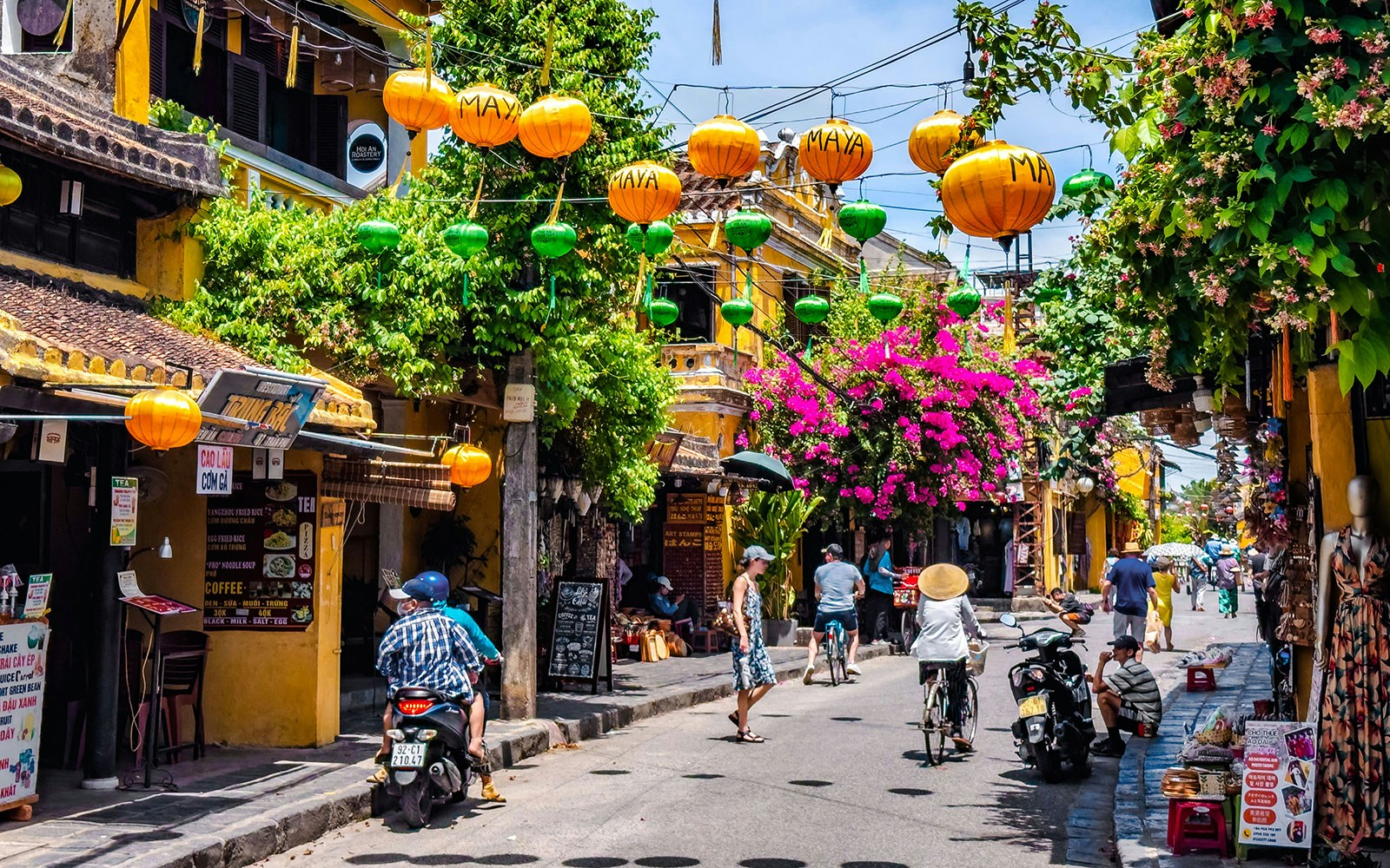 Street view in Hoi An ancient town, Vietnam, with colorful lanterns and vibrant flowers.