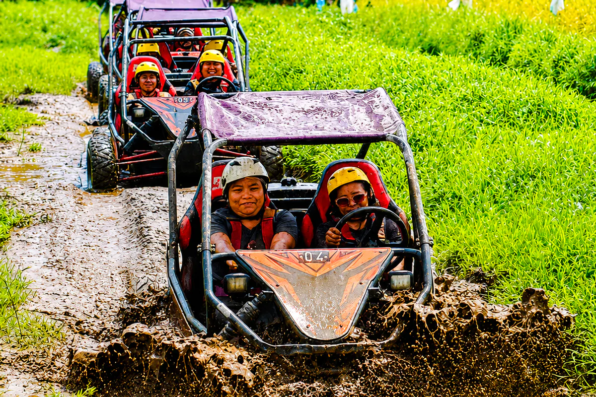 Buggy ride through muddy jungle track in Ubud, Bali, with lush green rice fields.