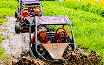 Buggy ride through muddy jungle track in Ubud, Bali, with lush green rice fields.