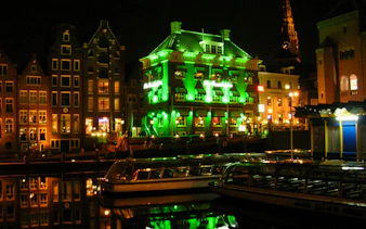 Canal-side buildings illuminated at night in Amsterdam's Red Light District.