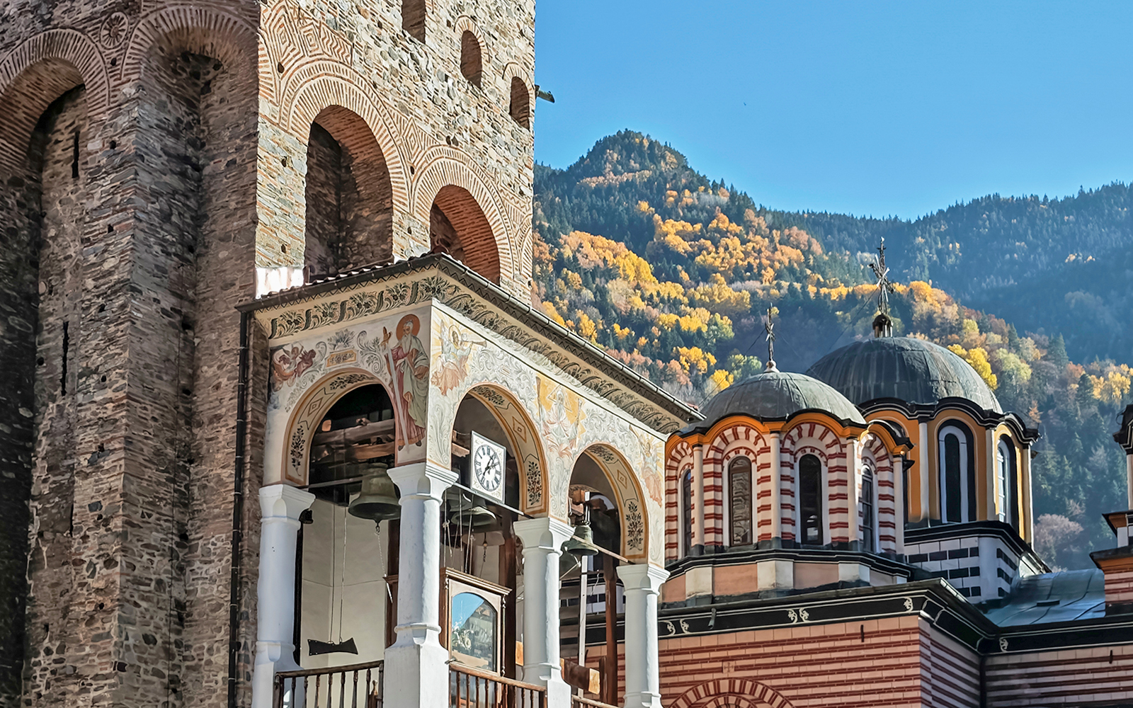 Hrelyo’s Tower and church domes at Rila Monastery, Bulgaria, with mountain backdrop.